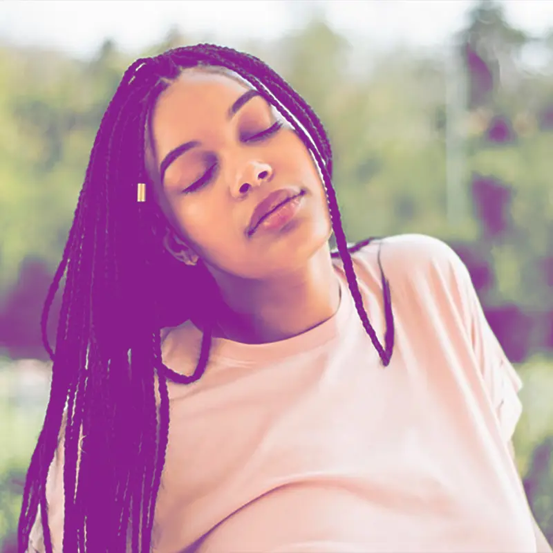 Black woman wearing braids with eyes closed relaxing after Christian Counseling services Tampa